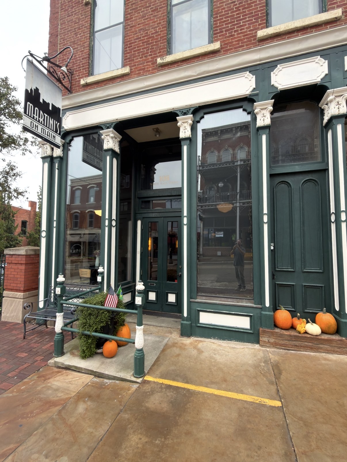 Martini's on Main storefront: a historic green-and-cream Victorian facade with tall windows and glass doors, a hanging Martini's on Main skyline sign and pumpkins on the sidewalk out front